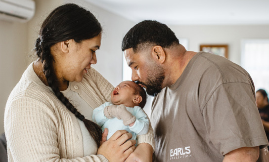 Samoan-Tongan parents kiss their newborn baby